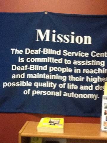 A photo captured by a person who is blind. A computer-generated caption for this photo is: A picture of a sign with a book on it.