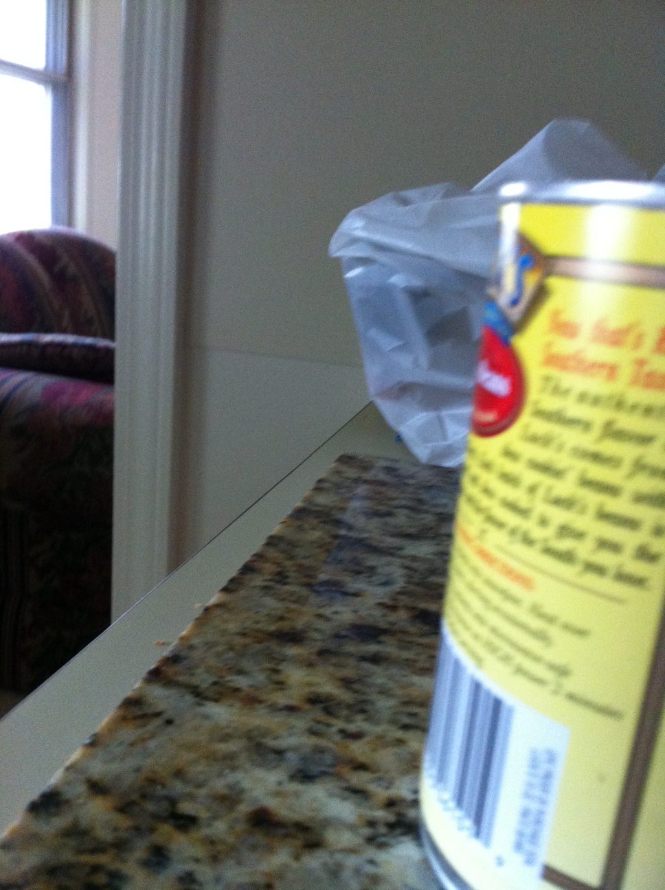 A photo captured by a person who is blind. A computer-generated caption for this photo is: A bottle of food sitting on top of a table.