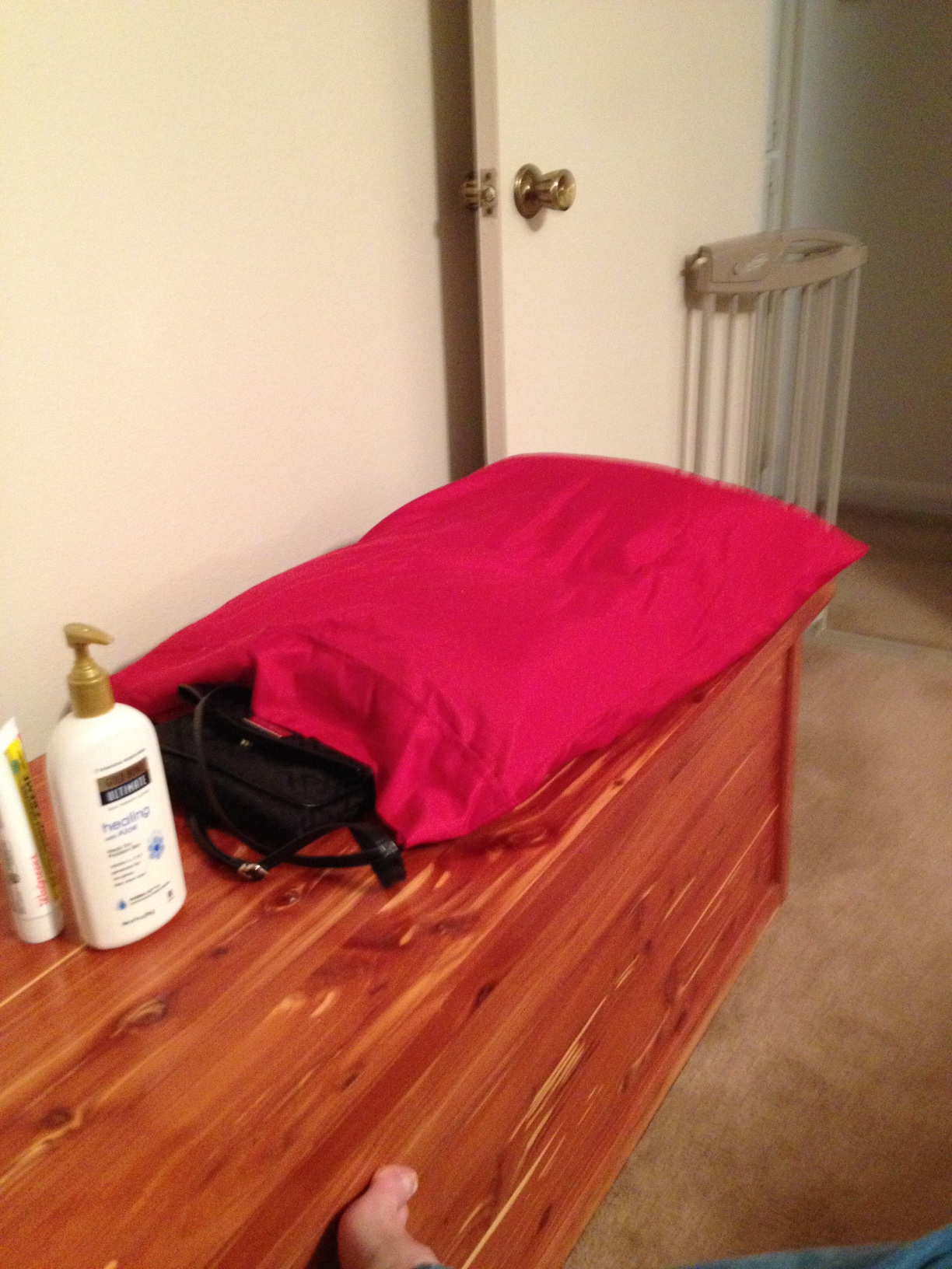 A photo captured by a person who is blind. A computer-generated caption for this photo is: A bedroom with a red bed and a bag.
