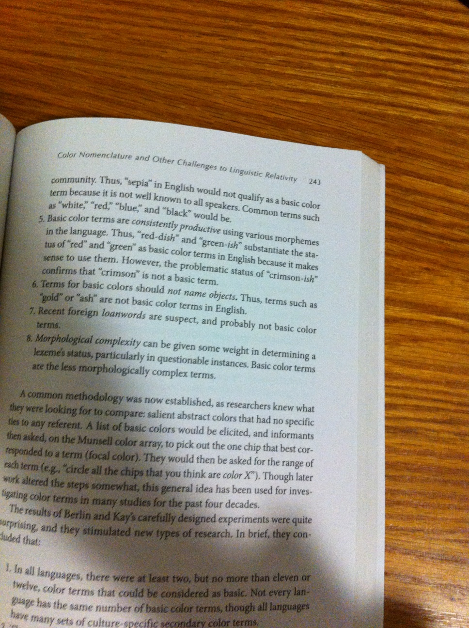 A photo captured by a person who is blind. A computer-generated caption for this photo is: An open book with an advertisement on a wooden table.