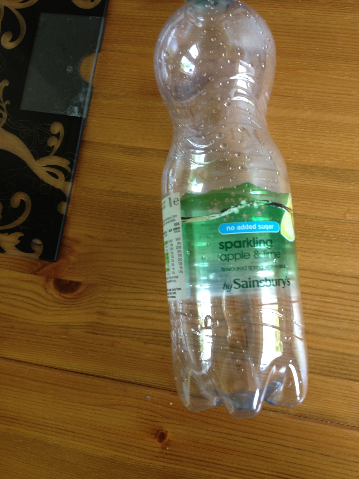 A photo captured by a person who is blind. A computer-generated caption for this photo is: A bottle of water sitting on a wooden table.