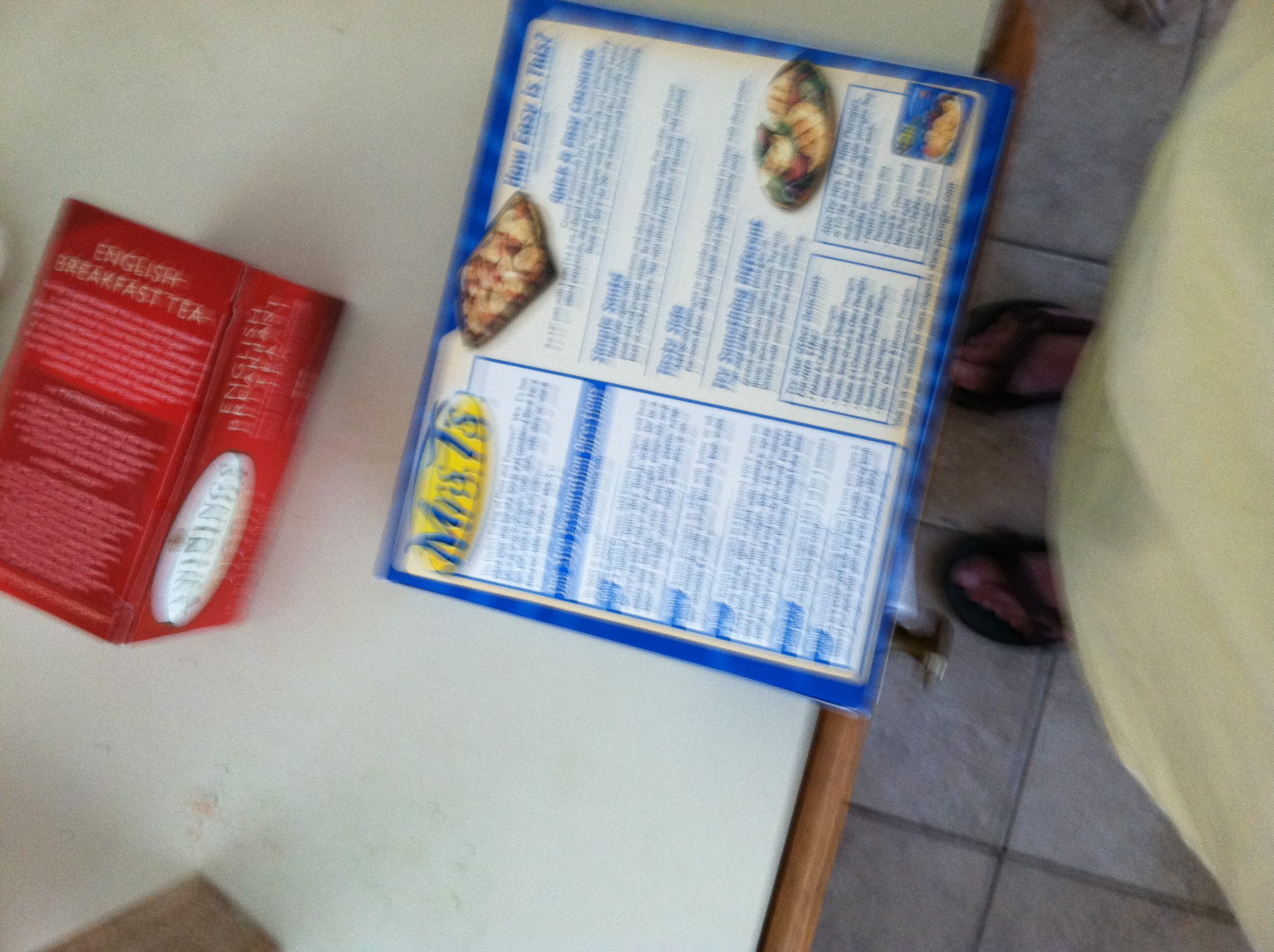 A photo captured by a person who is blind. A computer-generated caption for this photo is: A person sitting on a bed next to a book.