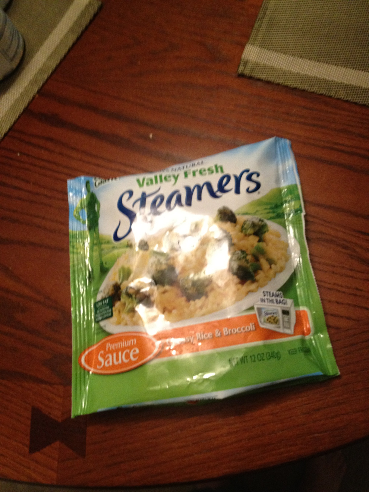 A photo captured by a person who is blind. A computer-generated caption for this photo is: A box of food is on a wooden table.