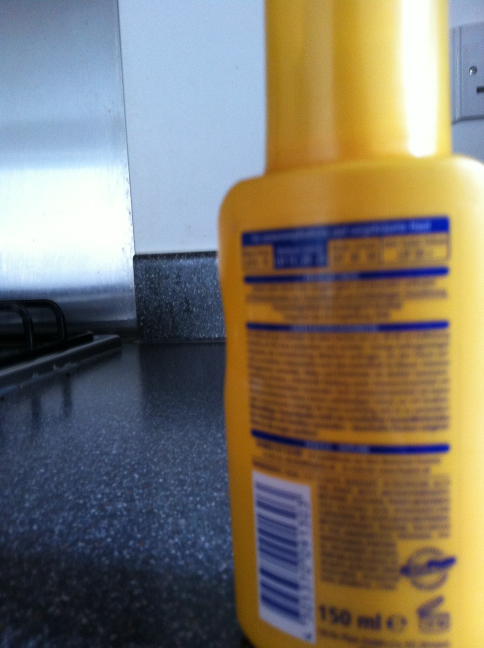 A photo captured by a person who is blind. A computer-generated caption for this photo is: A yellow bottle is sitting on a table.