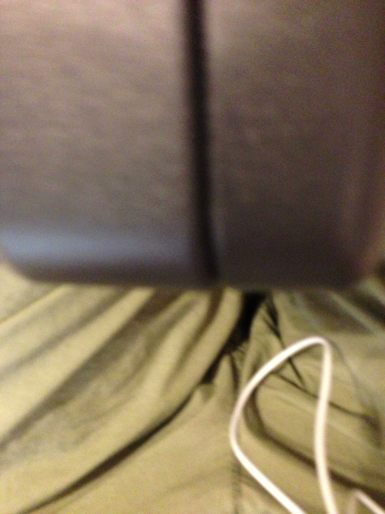 A photo captured by a person who is blind. A computer-generated caption for this photo is: A person sitting on top of a bed.